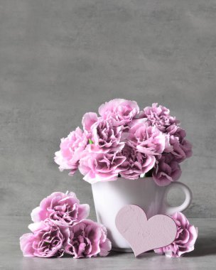 Картина, постер, плакат, фотообои "розовые гвоздичные цветы в чашке и сердце на сером фоне
. постеры", артикул 271300070