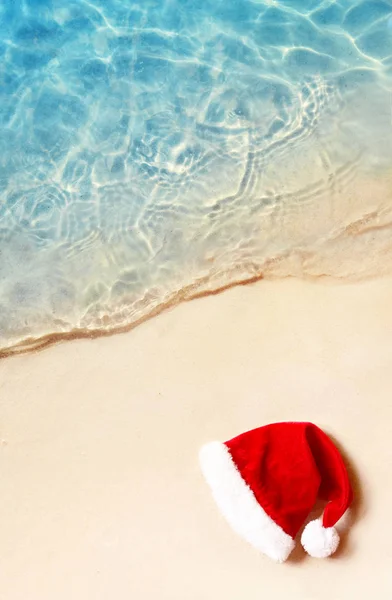 Concepto de vacaciones de Navidad. Vista superior del sombrero de Santa Claus en la playa de arena de verano . — Foto de Stock