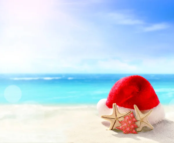 Concetto vacanze di Natale. Cappello Babbo Natale sulla spiaggia di sabbia estiva . — Foto Stock