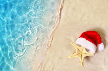 Noel tatili konsepti. Yaz kum plajında Noel Baba şapkalı denizyıldızının en iyi görünümü.