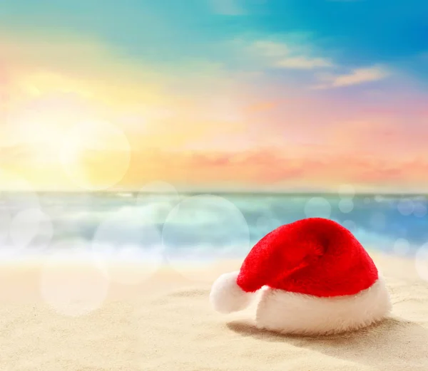Christmas holidays concept. Santa claus hat on summer sand beach — Stock Photo, Image