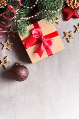 Noel arkaplanı, yeşil çam dalları, koniler ve gri arka planda hediye kutusu. Fotokopi alanı ve üst görünümü olan yaratıcı kompozisyon. Yeni yıl tatili, Noel..