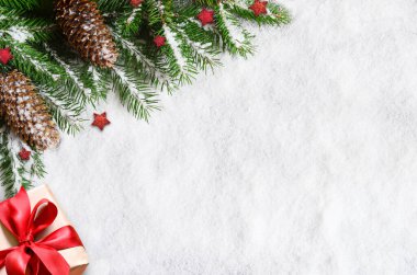 Noel arkaplanı, yeşil çam dalları, koniler ve karlı zeminde hediye. Sınır ve kopyalama alanı ile yaratıcı kompozisyon, üst görünüm. Yeni yıl, tatil, Noel, dekorasyon.