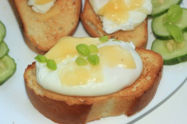 Haşlanmış yumurta tost baget slices.with beyaz bir plaka üzerinde bir salatalık üzerinde