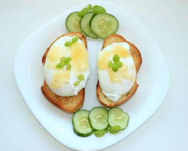 Haşlanmış yumurta tost baget slices.with beyaz bir plaka üzerinde bir salatalık üzerinde