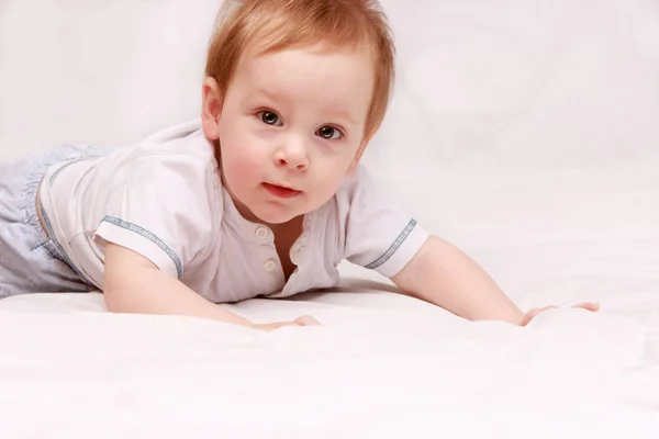 Retrato de um lindo bebê de 6 meses sorrindo, rastejando na cama — Fotografia de Stock