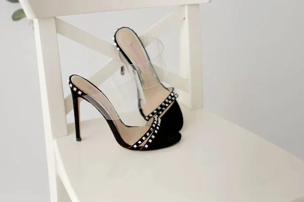 .piękne czarne sandały na obcasie z dżetów stojących na białym krześle. — Zdjęcie stockowe