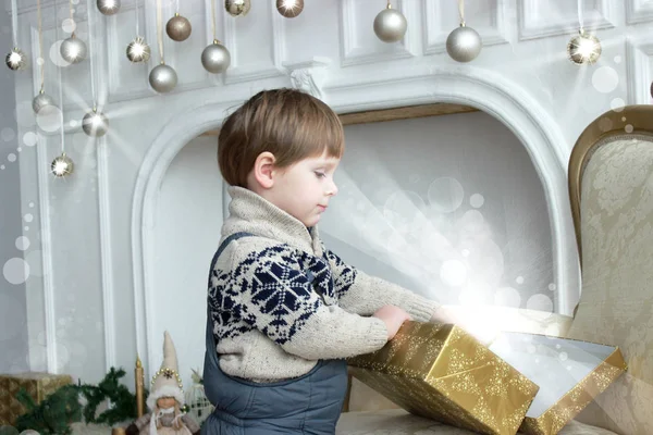 Urocze dziecko przez choinkę z obecnych polach. Happy Little dziecko otwarcie prezenty noworoczne z choinki niewyraźne światło na tle. Zimowe wakacje cuda. — Zdjęcie stockowe