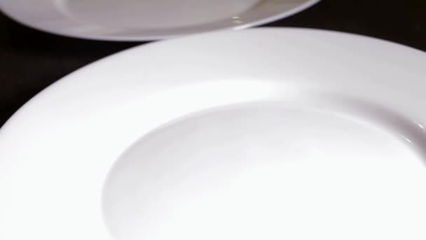 Auf einem weißen runden Teller grüne Salatblätter fallen — Stockvideo