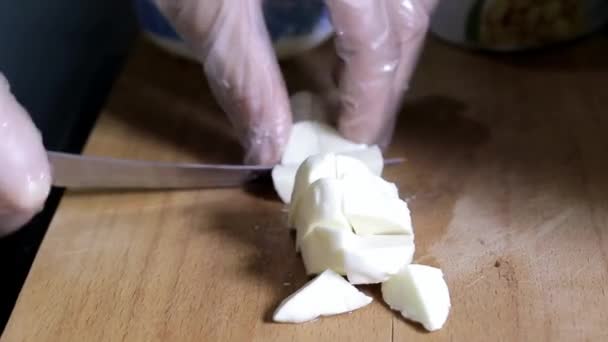 Рука в рукавичках нарізає сир кубиками — стокове відео