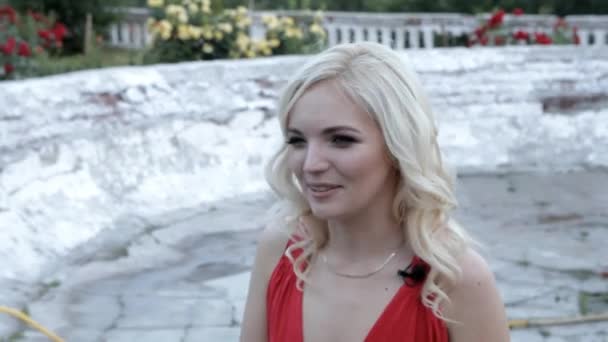 年轻的金发女孩在红色礼服情感叙述的背景下 一个古老的喷泉 — 图库视频影像