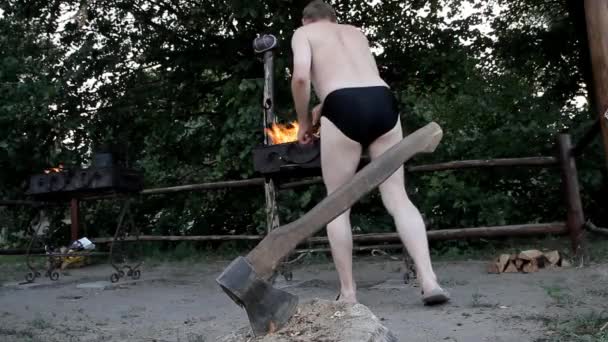 ショート パンツの男が火鉢で薪をスローします — ストック動画