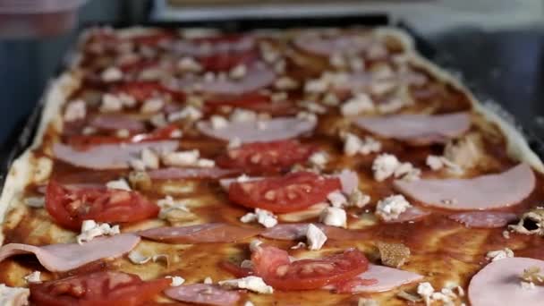 Na bardzo duży prostokątny pizza z mięsem boczek, pomidory i pieczarki umieścić plasterki sera — Wideo stockowe