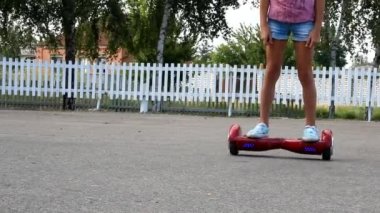 bir beyaz tahta çitin yanında kırmızı bir hoverboard bir kız geçer