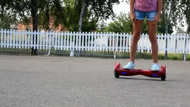 Una Chica Hoverboard Rojo Pasa Por Una Cerca Madera Blanca — Vídeo de stock