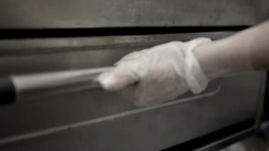 kadın el eldiven fırın açmak ve pizza koymak