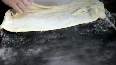 Kadınların elleri hamuru saran bir çarşafa serilmişti.