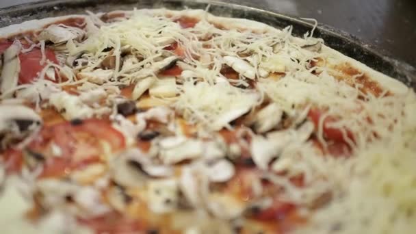 Weibliche Hand streut geriebene Käse-Pizza — Stockvideo