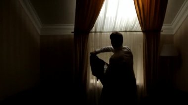 Pencerenin yanındaki genç adam iş ceketini giyer.