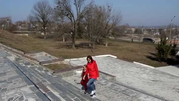 Мама и дочь в красной одежде поднимаются по лестнице и делают селфи. — стоковое видео