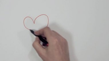 erkek el beyaz bir levha üzerinde iki kalp çizer