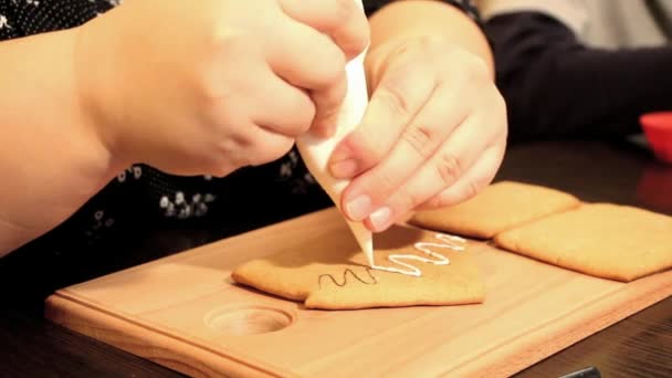 Thick female hands squeeze the cream out of the package on the gingerbread — Stock Video