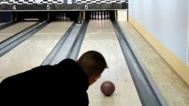 koyu renk giysiler içinde genç bir bowling topu atma, arka görünümü