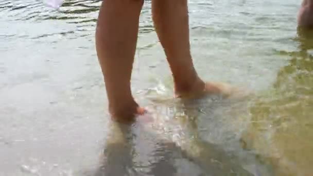 女性の足は泥だらけの川の水の中に立つ — ストック動画