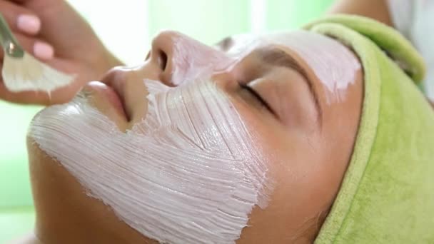 Kosmetikerin Hand fügt einem Mädchen eine Maske zu, sehr nah — Stockvideo
