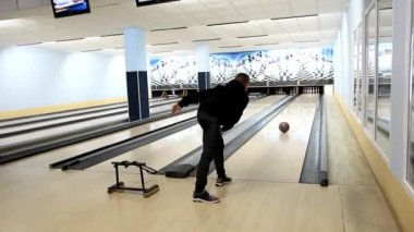koyu renk takım elbiseli genç adam kulis bowling bowling topu atar