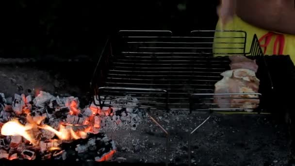 火の光の中で男性の手はグリルに生の肉を置く — ストック動画