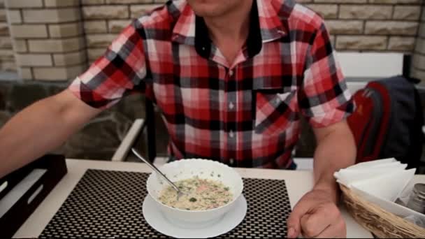 Mies kirkkaassa paidassa juo olutta lounaan aikana — kuvapankkivideo