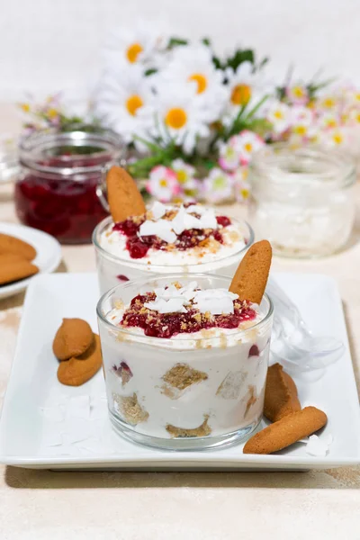 dessert in a glass with cookies, cream and jam, vertical closeup