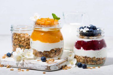 müsli, tatlılar meyve püresi ve meyve üzerinde beyaz masa, closeup kavanozlara