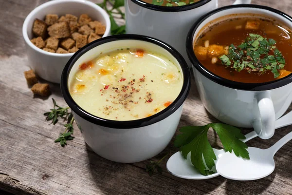 hot soups in mugs on wooden table, top view