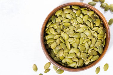 Beyaz arka planda, closeup üstten görünüm kabak çekirdeği ile kase