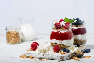 beyaz masa, yatay olarak kavanozlara tatlılar granola, berry ve meyve püresi