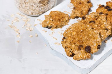 Beyaz ahşap tahta, üstten görünüm üzerinde üzümlü ev yapımı yulaf ezmeli kurabiye