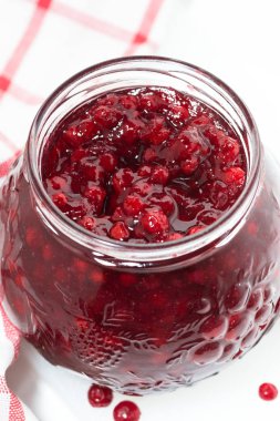 kızılcık cam kavanoz reçel beyaz bir tabloda, üstten görünüm