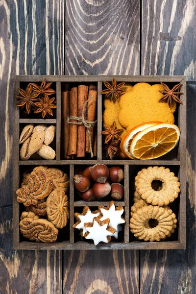 wooden box with Christmas sweets and spices on wooden background, top view