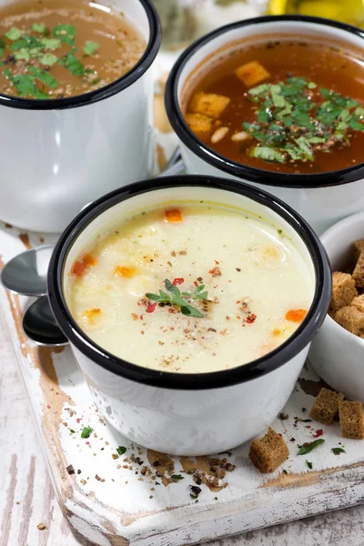 assortment of hot soups in mugs, top view