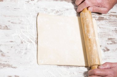 hamuru haddeleme işlemi. El ve oklava, üstten görünüm