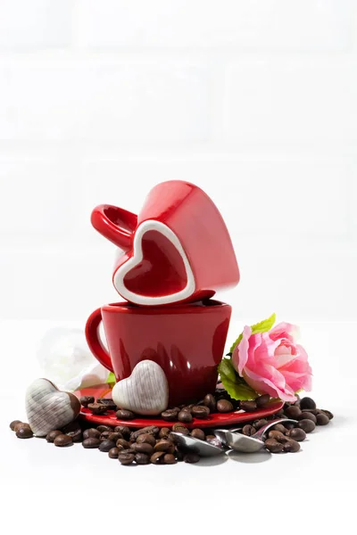 Tazze rosse e caramelle al cioccolato sotto forma di cuore su bac bianco — Foto Stock