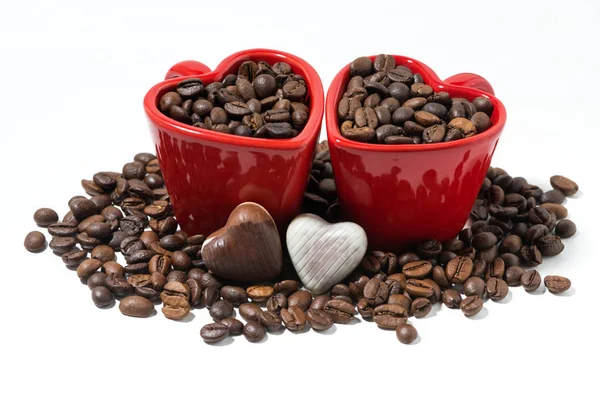 Rote Tassen mit Kaffeebohnen und Schokoladenbonbons in Form von — Stockfoto