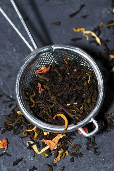 dry black tea with herbs in a strainer, closeup