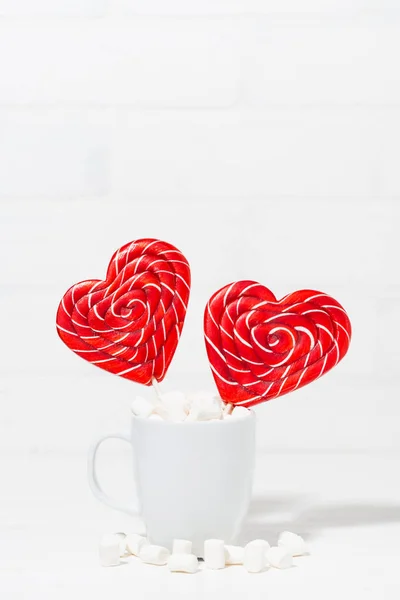 candy on a stick in the form of hearts in a cup on white background, vertical top view