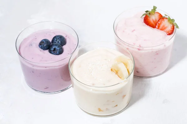 Солодкі йогурти з фруктами та ягодами на білому тлі, зверху — стокове фото