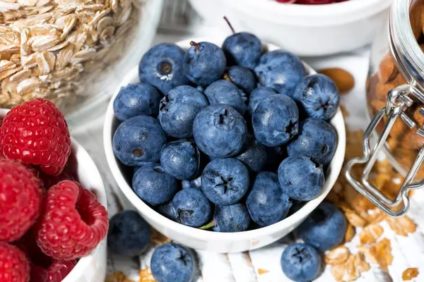 Fresh blueberries, raspberries and breakfast, top view — Stock Photo, Image