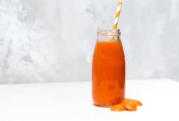 新鲜的胡萝卜汁在一个瓶子在白色背景, 特写镜头 免版税图库照片