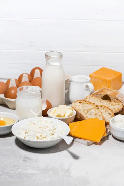 Sortimento de produtos lácteos agrícolas frescos na mesa branca, vertical — Fotografia de Stock